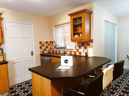 a kitchen with a counter with chairs and a table at 6 Knightshaven Holiday Village - Valentia Island in Knights Town