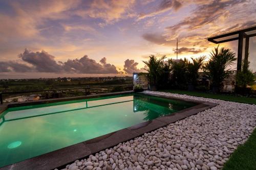 a swimming pool with a sunset in the background at Casa Jenah Three Bedroom Villa in Kesiman