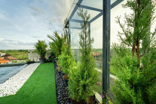 een glazen huis met een tuin met bomen en gras bij Casa Jenah Three Bedroom Villa in Kesiman
