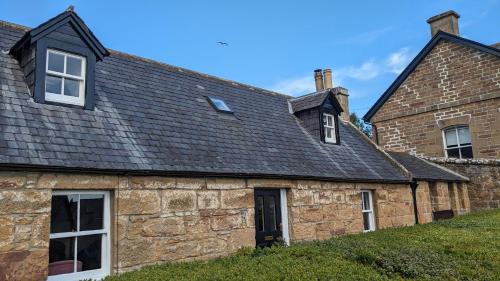 an old stone house with a black roof at Historic character cottage in central Dornoch in Dornoch