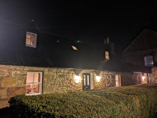 a stone house at night with lights on it at Historic character cottage in central Dornoch in Dornoch