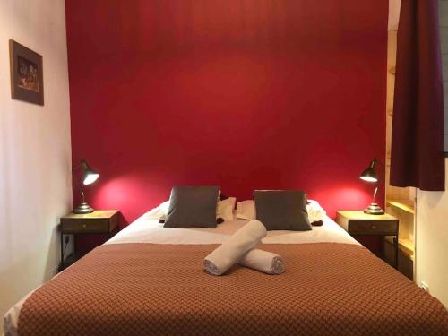 a bedroom with a large bed with a red wall at Appartement pour 2 personnes à 50 mètres du port in Paimpol