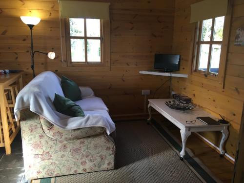 a living room with a couch and a table at Trevenna Cabin in St Austell