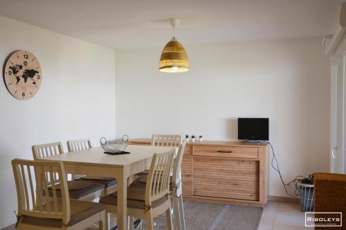 une salle à manger avec une table, des chaises et une télévision dans l'établissement Marina Lodge - Villa climatisée avec piscine, à Vias