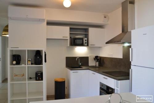 une cuisine avec des armoires blanches et un micro-ondes dans l'établissement Marina Lodge - Villa climatisée avec piscine, à Vias