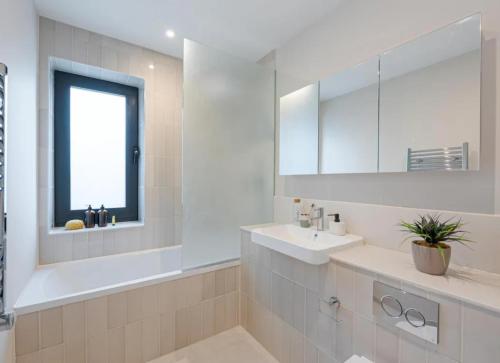 a white bathroom with a sink and a mirror at Kings Mews Elegance: City Sparrow's Premier 2-Bedroom Residences in London