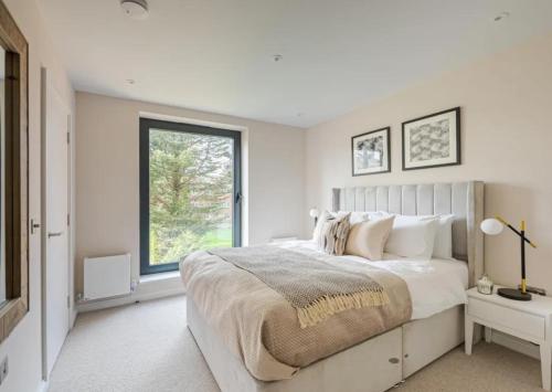 a white bedroom with a large bed and a window at Kings Mews Elegance: City Sparrow's Premier 2-Bedroom Residences in London
