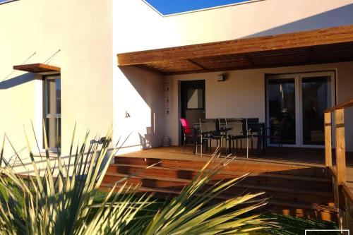 une maison avec une terrasse en bois et une salle à manger dans l'établissement Villa T3 à 400m de la plage avec piscine, à Vias