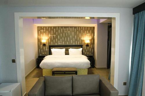 sypialnia z łóżkiem i kanapą przed nim w obiekcie KABC Hotel w mieście Kigali