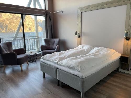 a bedroom with a bed and two chairs and a window at Værlandet Havhotell in Hamna