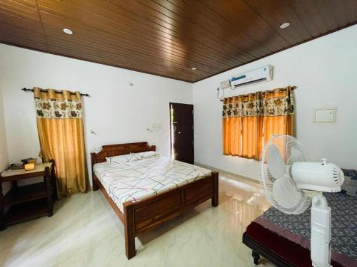 1 dormitorio con 1 cama y ventilador. en Appu's Abode en Kollam