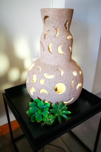 a vase sitting on a table with a green plant at Klinkies in Potchefstroom