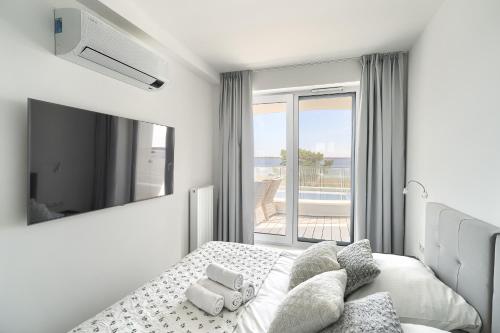 a white bedroom with a bed and a large window at SandLand - Rogowo Pearl in Rogowo