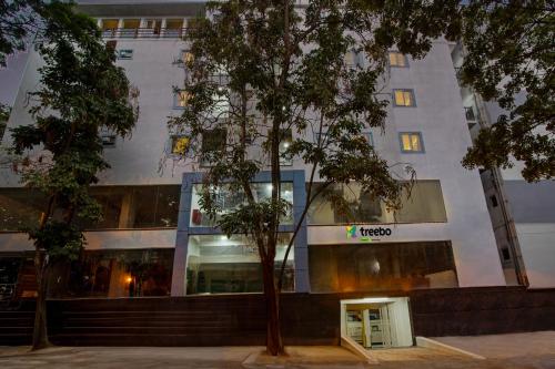 a building with a tree in front of it at Treebo Global Stay, Jayanagar in Bengaluru