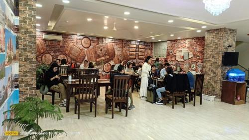 a group of people sitting at tables in a restaurant at Hotel D'Capitol - Delhi Airport in New Delhi