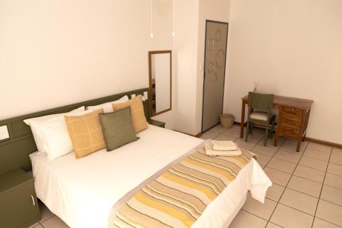 a bedroom with a bed and a desk and a chair at Klinkies in Potchefstroom