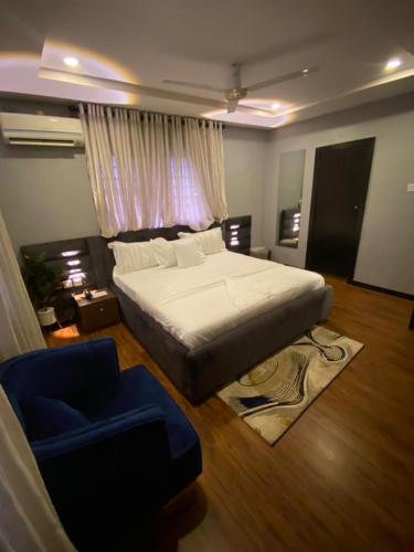 um quarto com uma cama grande e uma cadeira azul em KAFT2 HOTELS em Ijebu Ode