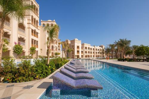 a swimming pool with a row of umbrellas next to buildings at Grand Palace - Adults only 18 years plus in Hurghada