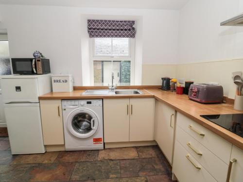 a kitchen with a washing machine and a sink at Tyne View Cottage in Hexham
