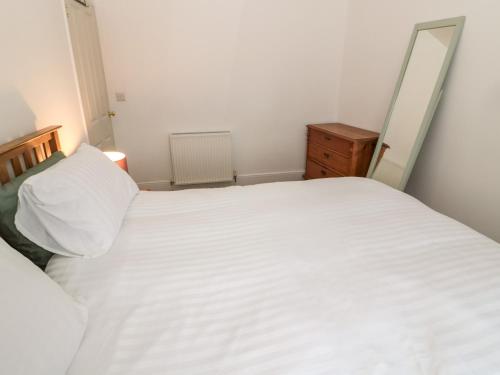 a bedroom with a large white bed and a dresser at Tyne View Cottage in Hexham
