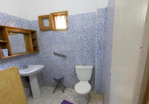 a blue tiled bathroom with a toilet and a sink at Villa keur Fatou in Sali Nianiaral