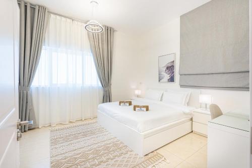 a white bedroom with a white bed and a window at Luxurious Home in Silicon with Stylish Interior in Dubai