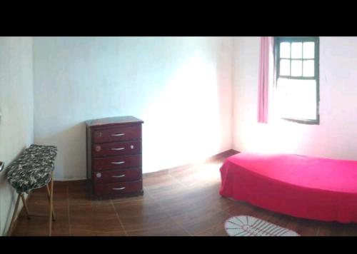 a bedroom with a red bed and a dresser at Chácara lua e sol in Pouso Alegre