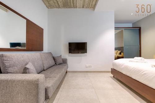 a living room with a couch and a bed at The Swieqi Poolside Suites in Is-Swieqi