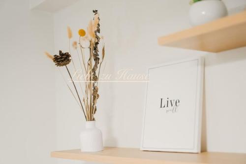 a white vase with flowers in it on a shelf at 2 BR Unit in the heart of Iloilo Self Check-in in Iloilo City