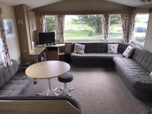 a living room with a couch and a table at 6-8 berth caravan, Perran Sands Haven Holiday Park, Cornwall in Perranporth