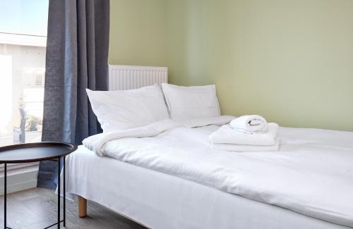 a bed with white sheets and a towel on it at Lasek Marceliński Fiqus Studio in Poznań