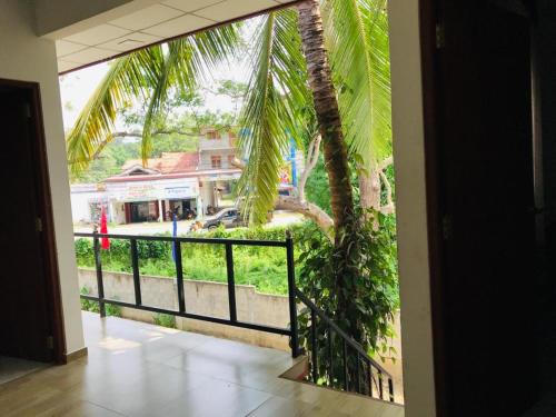 a room with a balcony with a palm tree at Tashil Hotel & Restaurant in Tissamaharama