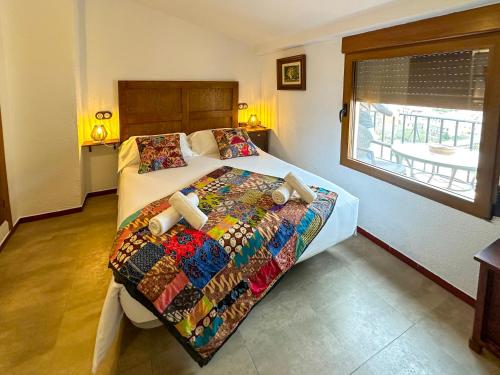 a bedroom with a bed with a colorful comforter and a window at Casa del Juez, Alojamiento rural singular in Alcalá del Júcar
