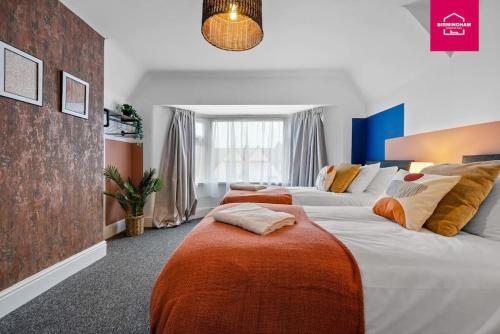 ein Hotelzimmer mit zwei Betten mit orangefarbenen Kissen in der Unterkunft Accessible ground floor wet room and bedroom in a modern 4 Bedroom House-B28 Hall Green in Birmingham