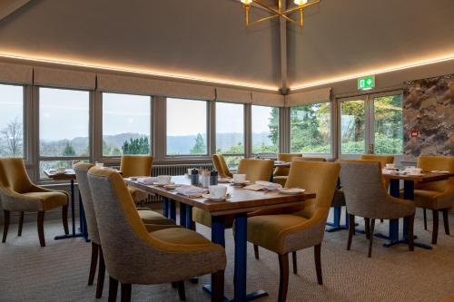 a dining room with tables and chairs and windows at Lindeth Fell Country House in Bowness-on-Windermere
