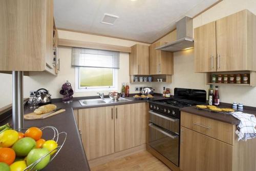 a kitchen with wooden cabinets and a bowl of fruit at The Derwent in Prestatyn