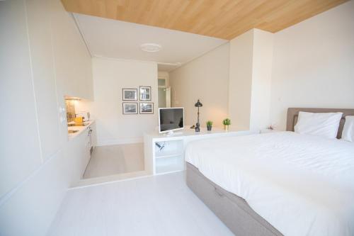 een witte slaapkamer met een bed en een televisie bij Porto D'Alma Santa Catarina Apartments in Porto