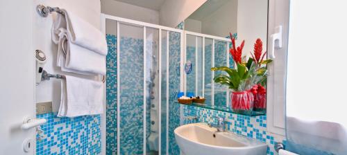 ein blau gefliestes Bad mit einem Waschbecken und einem Spiegel in der Unterkunft Hotel Sirius Riccione in Riccione