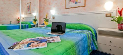 ein Schlafzimmer mit einem Bett und einem Laptop darauf in der Unterkunft Hotel Sirius Riccione in Riccione