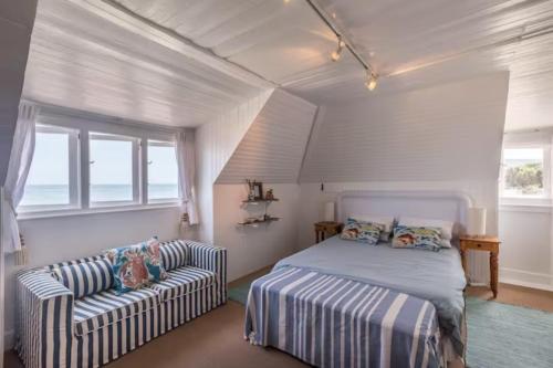 um quarto com uma cama, um sofá e janelas em Lorelei On The Beach em Kommetjie