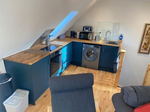a kitchen with blue cabinets and a washing machine at The Cartlodge in Debenham