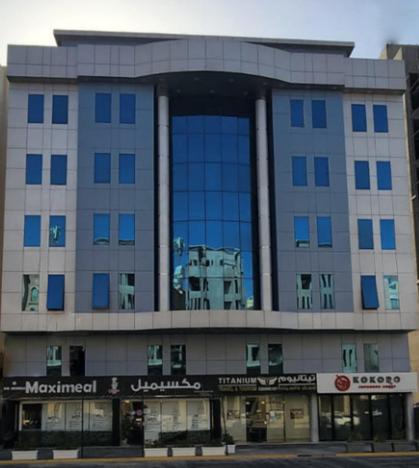 a large building with blue windows on a street at Yan Furnished Apartments in Al Khobar