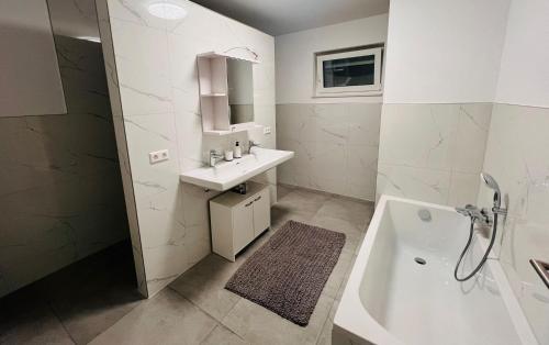 Baño blanco con lavabo y bañera en Apartment Weikersheim III en Weikersheim