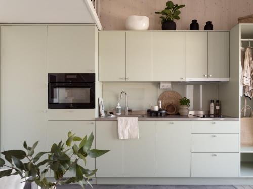 a white kitchen with white cabinets and a plant at Waterfront Cabins in Gothenburg