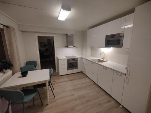 cocina con armarios blancos, mesa y sillas en Vardø accommodation - white house, en Vardø