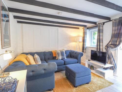 a living room with a blue couch and a tv at The Coach House Newcastle Emlyn in Newcastle Emlyn