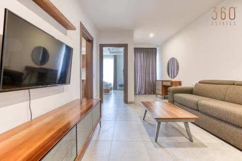 a living room with a large flat screen tv on a wall at The Swieqi Poolside Suites in Is-Swieqi