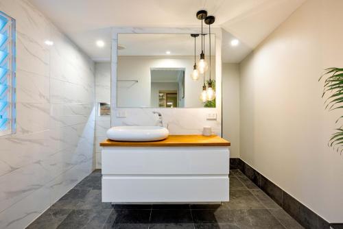 a bathroom with a sink and a mirror at City Haven - A Slice of Paradise Fringing the CBD in Cairns