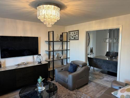 uma sala de estar com um sofá, uma televisão e um lustre em The JN Grove em Peterborough