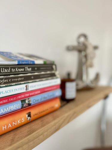 a stack of books sitting on a shelf at Sealladh Na Mara, Pittenweem in Pittenweem